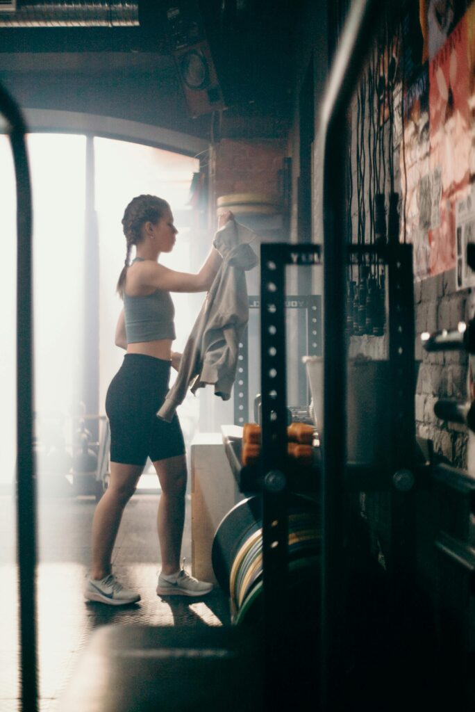 A young woman in a gym setting getting ready for a workout, wearing athletic attire.