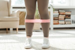 A plus-size woman working out indoors using a resistance band for fitness training.