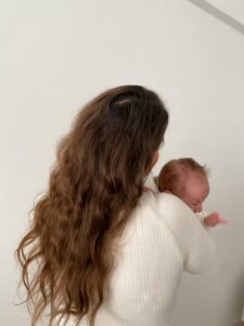 A mother lovingly holds her newborn baby indoors, showcasing warmth and family bonding.