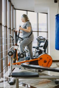 An adult woman using an elliptical trainer in a bright, modern gym.