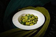 Delicious rigatoni pasta with creamy pesto sauce adorned with pine nuts, elegantly served.