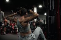 Woman performs strength training with a cable machine in a modern gym setting.